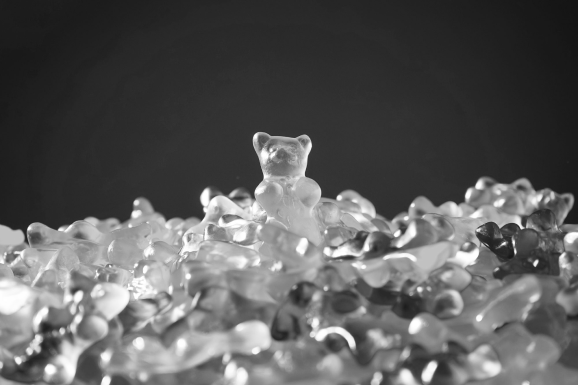 black and white photo of gummy bears with one at the centre